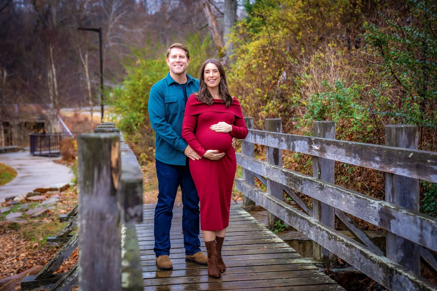 Couple walking together on a wooden boardwalk surrounded by autumn trees.