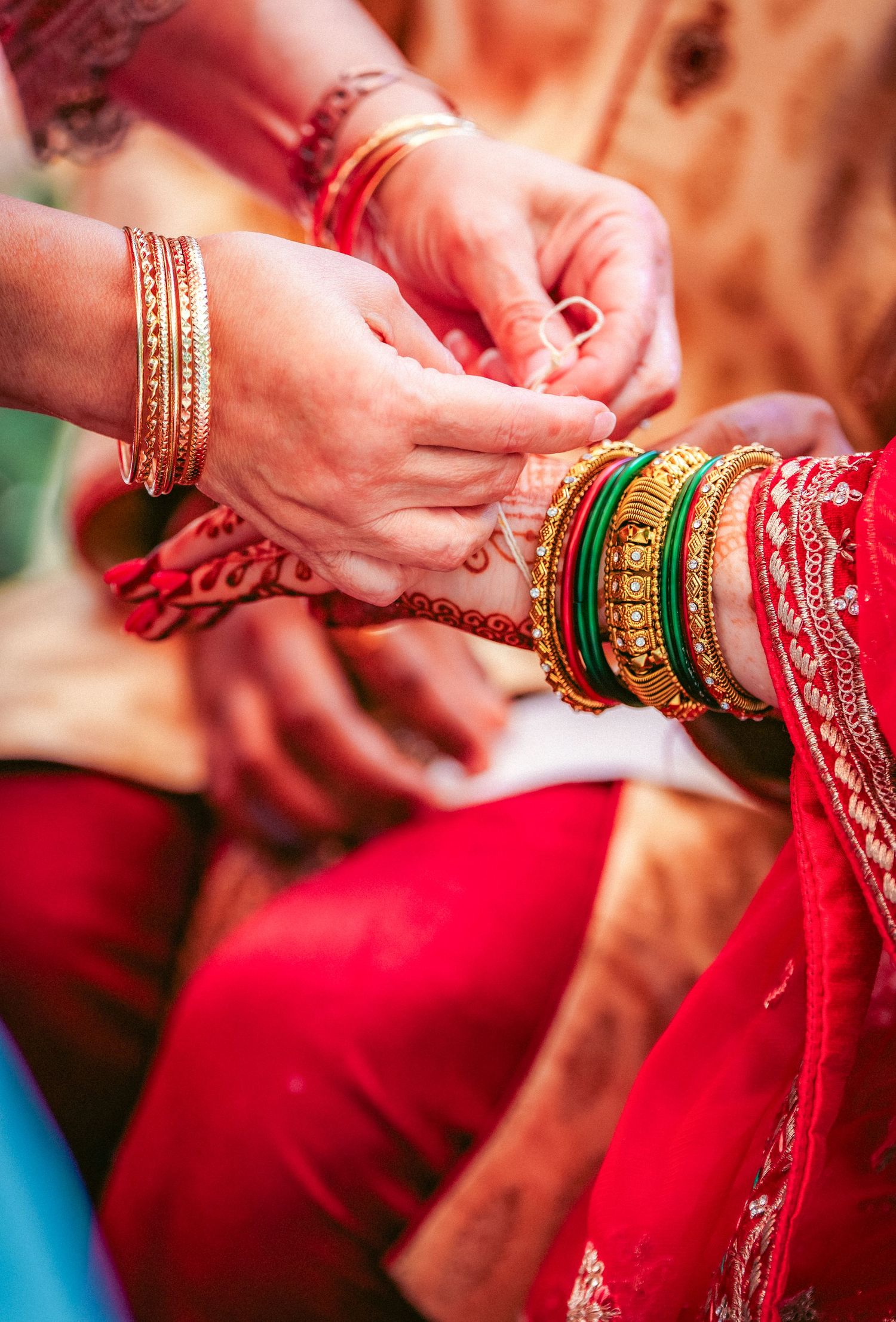 Close-up of hands wearing colorful bangles and traditional Indian bridal jewelry.