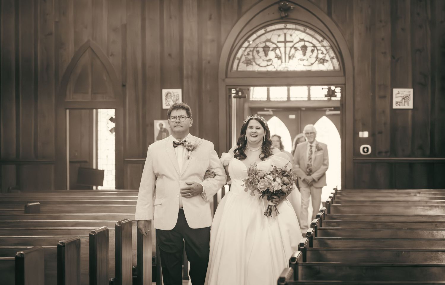 Traditional church interior with wooden pews and arched doorways during a wedding ceremony.