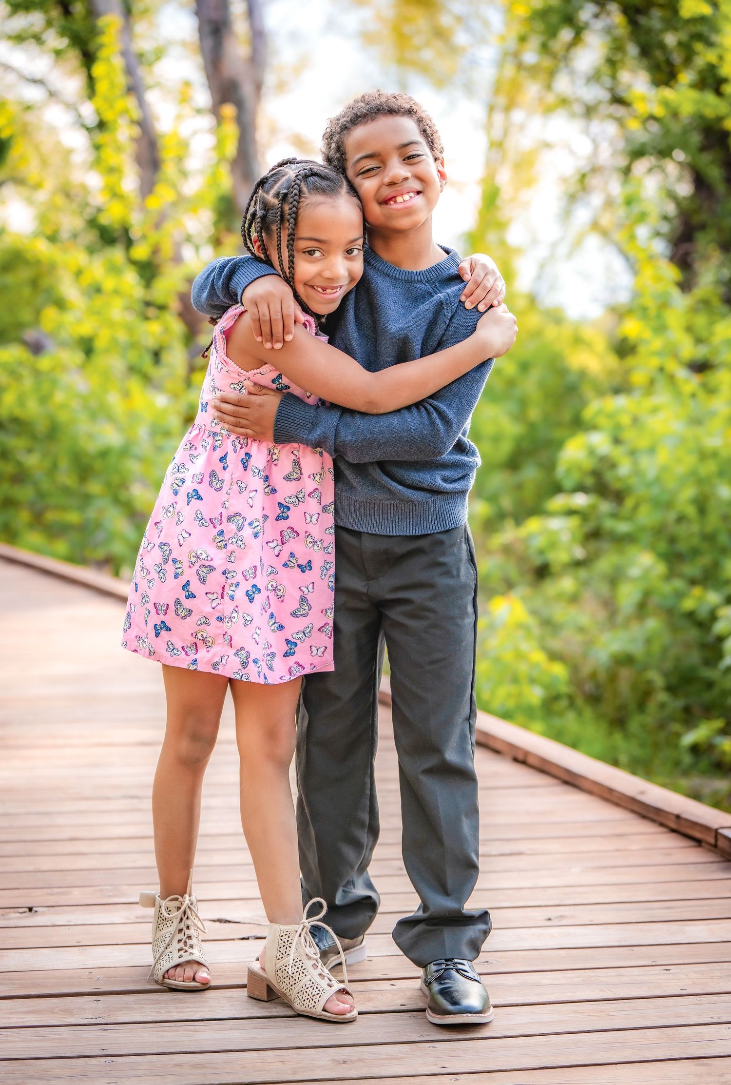 Sweet sibling moment captured on a wooden boardwalk during sunset.