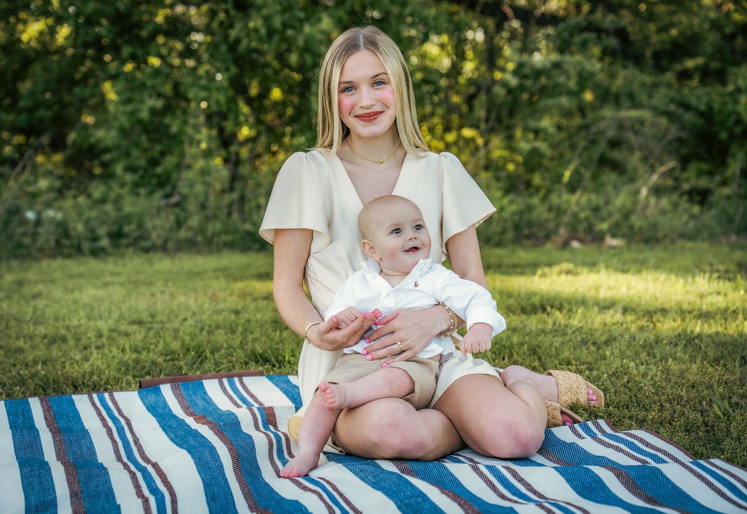 Family shares joyful moments together on striped blanket outdoors.