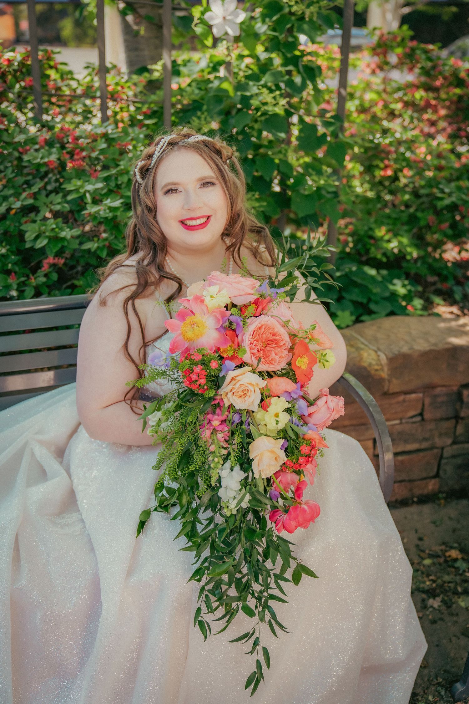 Beautiful bridal bouquet featuring coral, pink and peach flowers with cascading greenery.