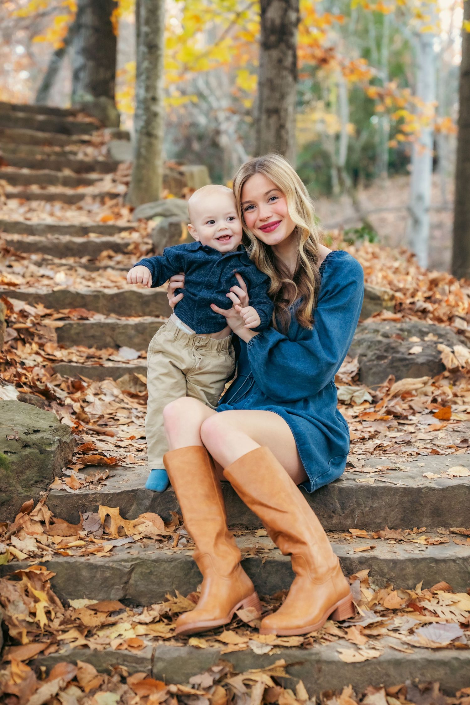 Fall family photo on stone steps covered in leaves, featuring brown boots and casual attire.