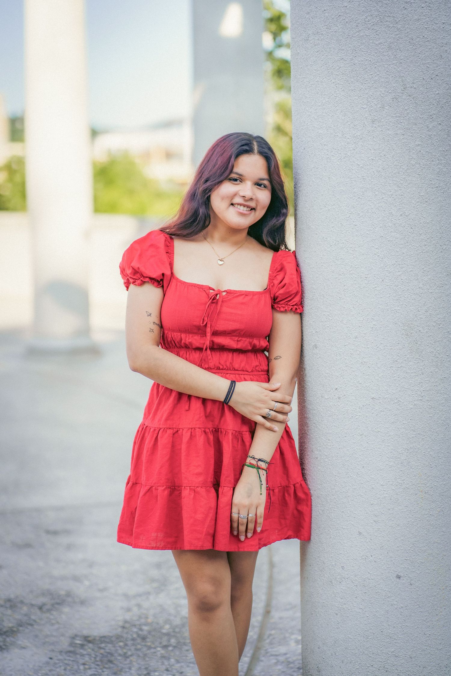 Red summer dress styled against white columns in outdoor photoshoot.