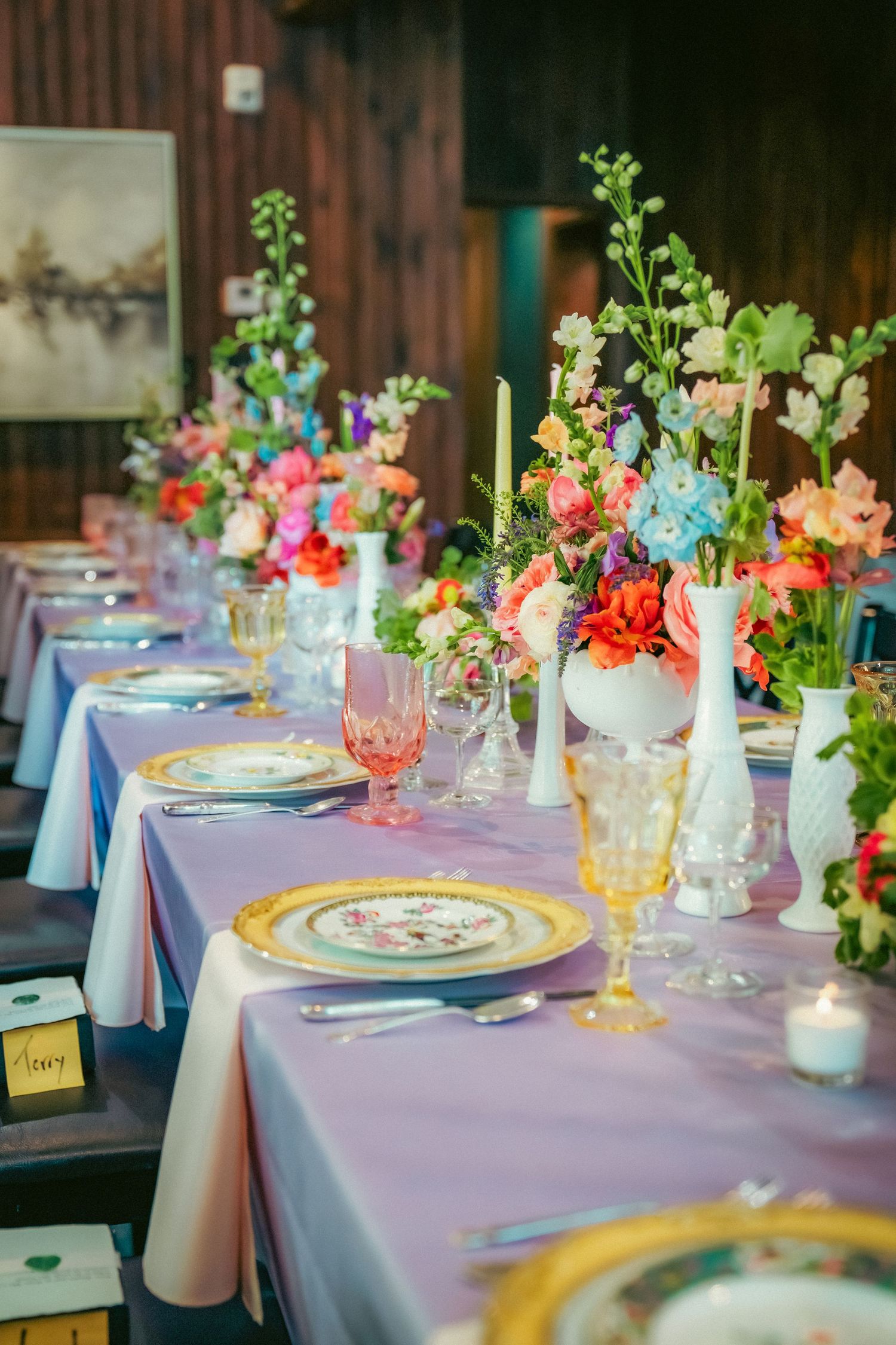 Wedding reception tables decorated with lavender tablecloths and vibrant spring flower arrangements.