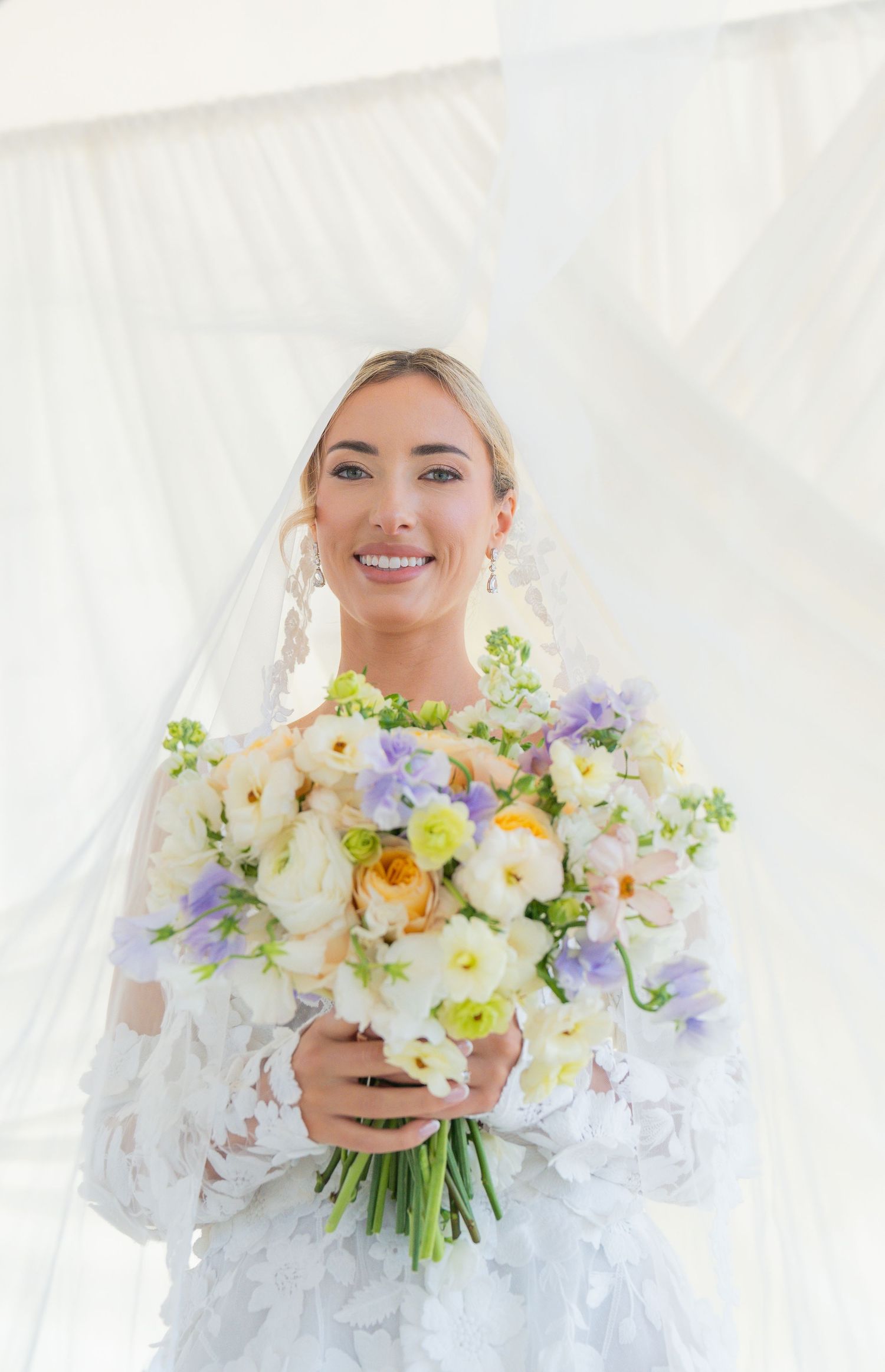 Close-up bridal portrait with pastel spring bouquet featuring purple and yellow blooms.