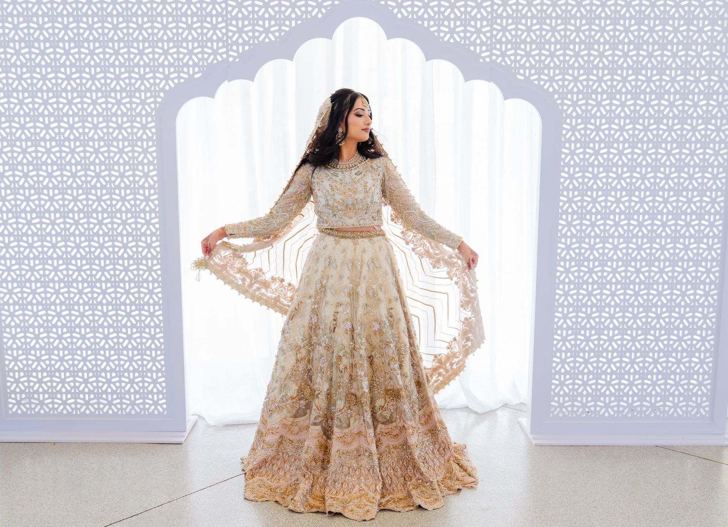 Bride in flowing cream lehenga twirling to show full skirt detail.