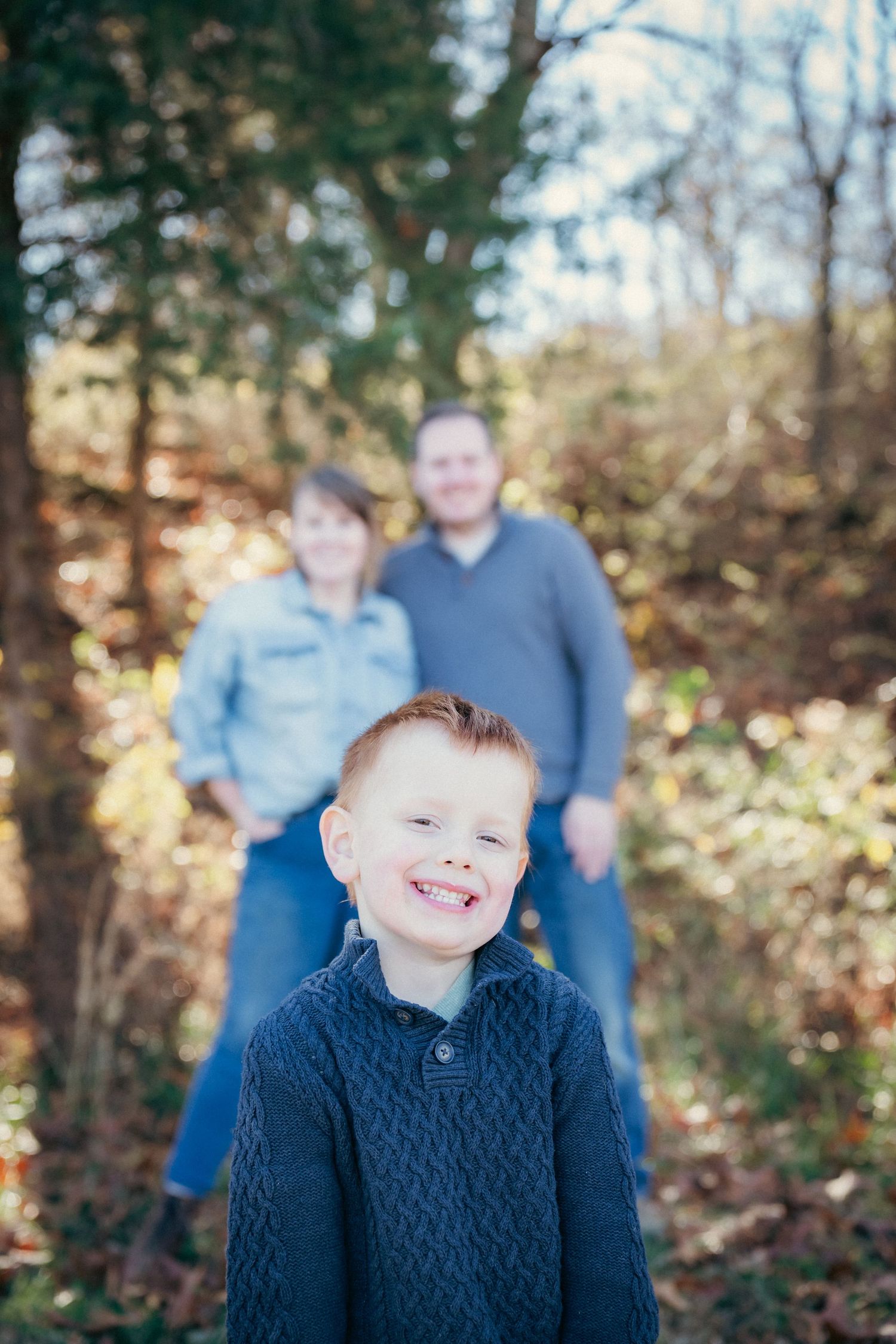 Candid family autumn portrait session in wooded setting with natural lighting.
