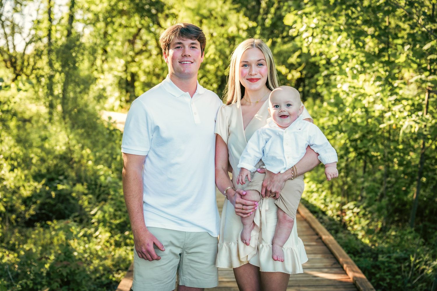 Family portrait session on wooden walkway surrounded by lush greenery.