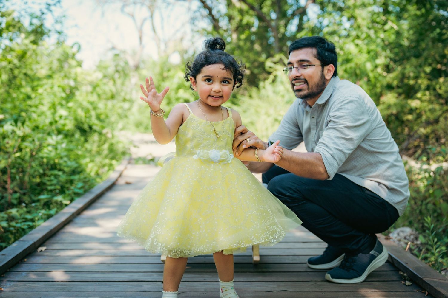 A family shares playful moments together on a wooden walkway in a natural setting.