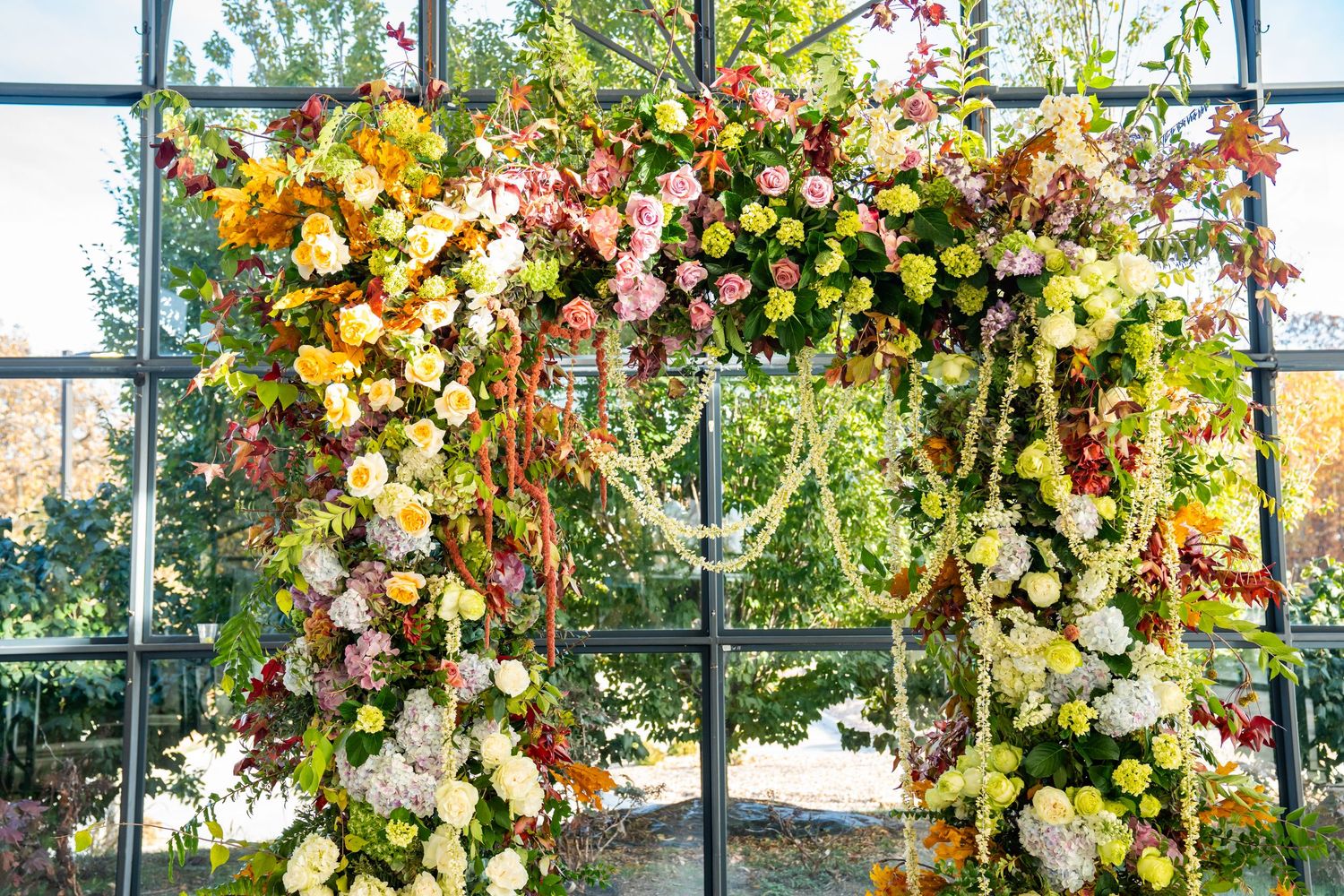 Ornate floral wedding arch featuring yellow and pink roses with cascading greenery.