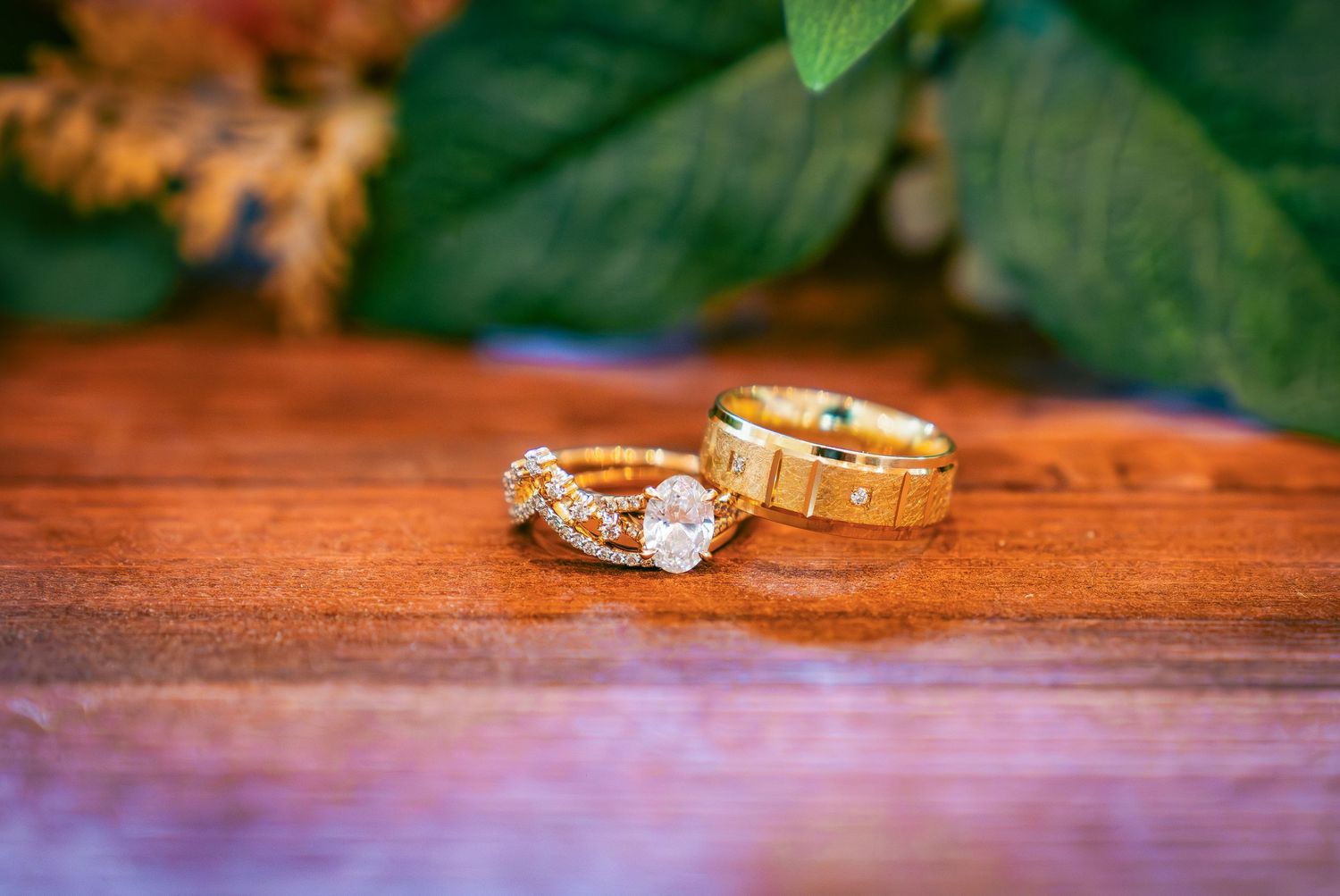 Wedding rings and jewelry displayed on a wooden surface with natural lighting.