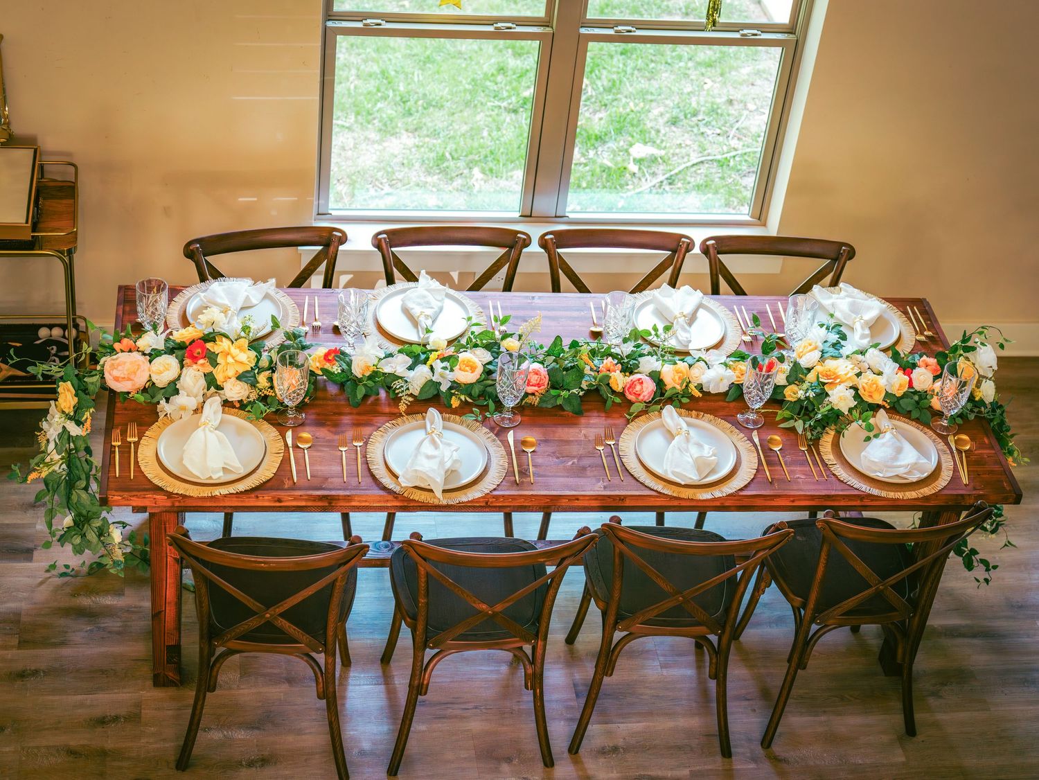 Rustic wooden chairs decorated with floral garlands at a wedding reception table.
