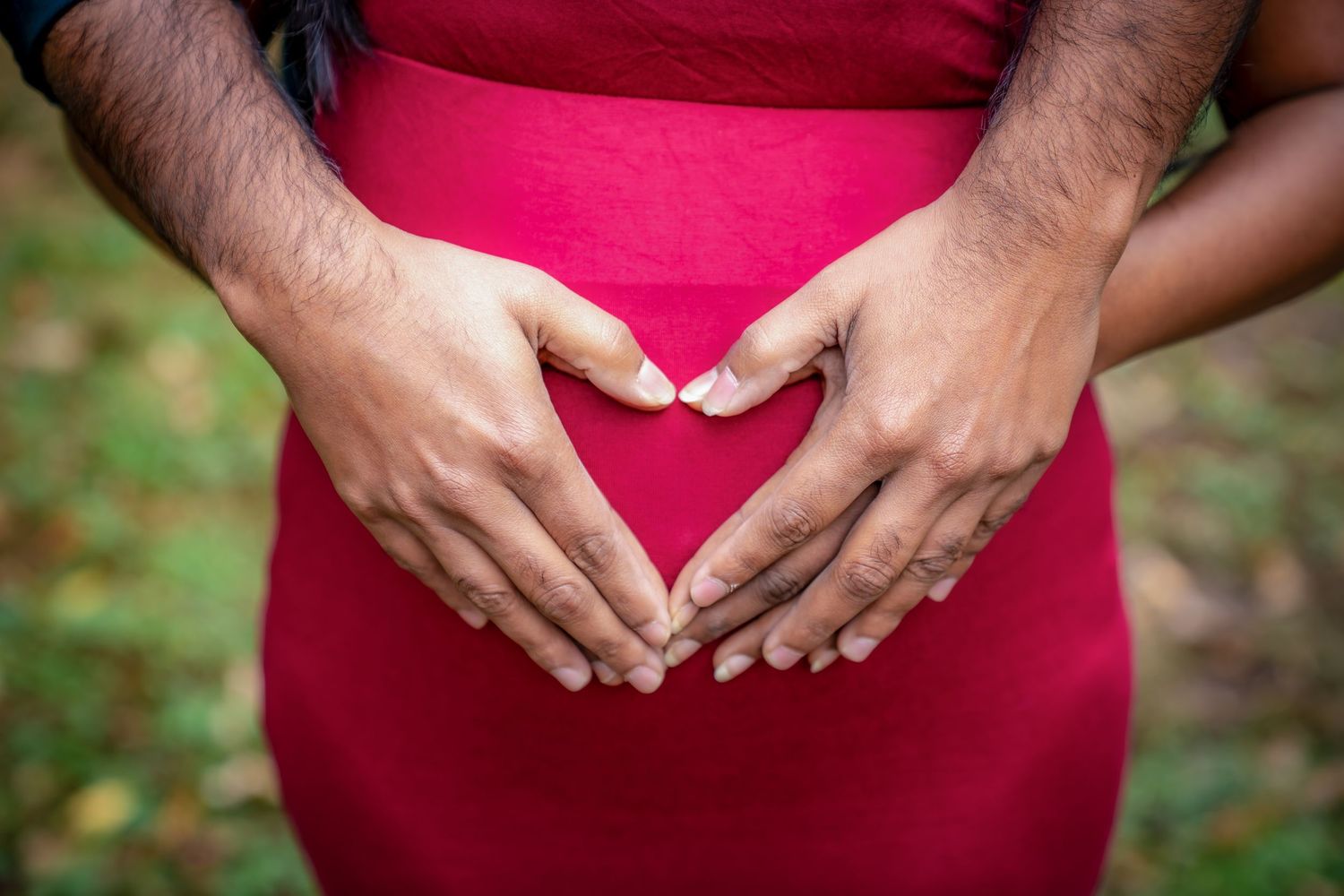 Multiple close-up shots showing hands forming heart shapes against red fabric.