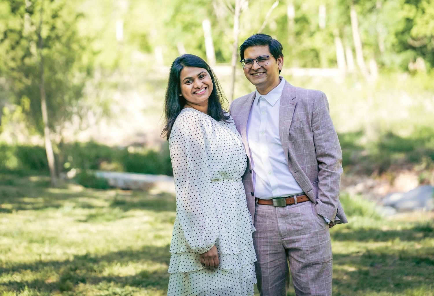 Spring engagement photo of couple in polka dot dress and suit outdoors.
