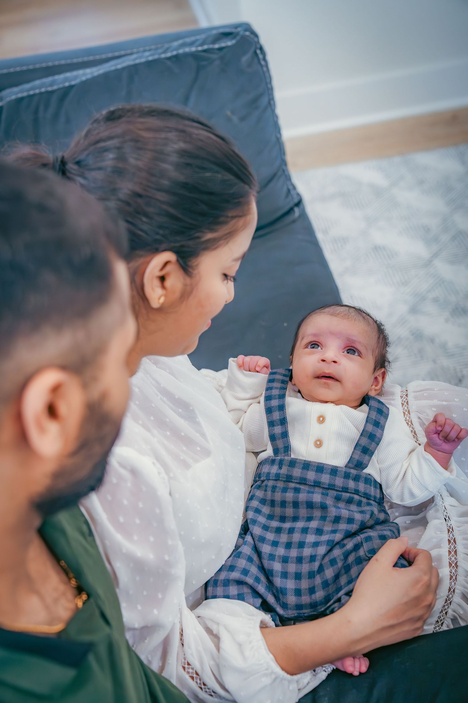 Baby in checkered outfit gazes up during tender moment.