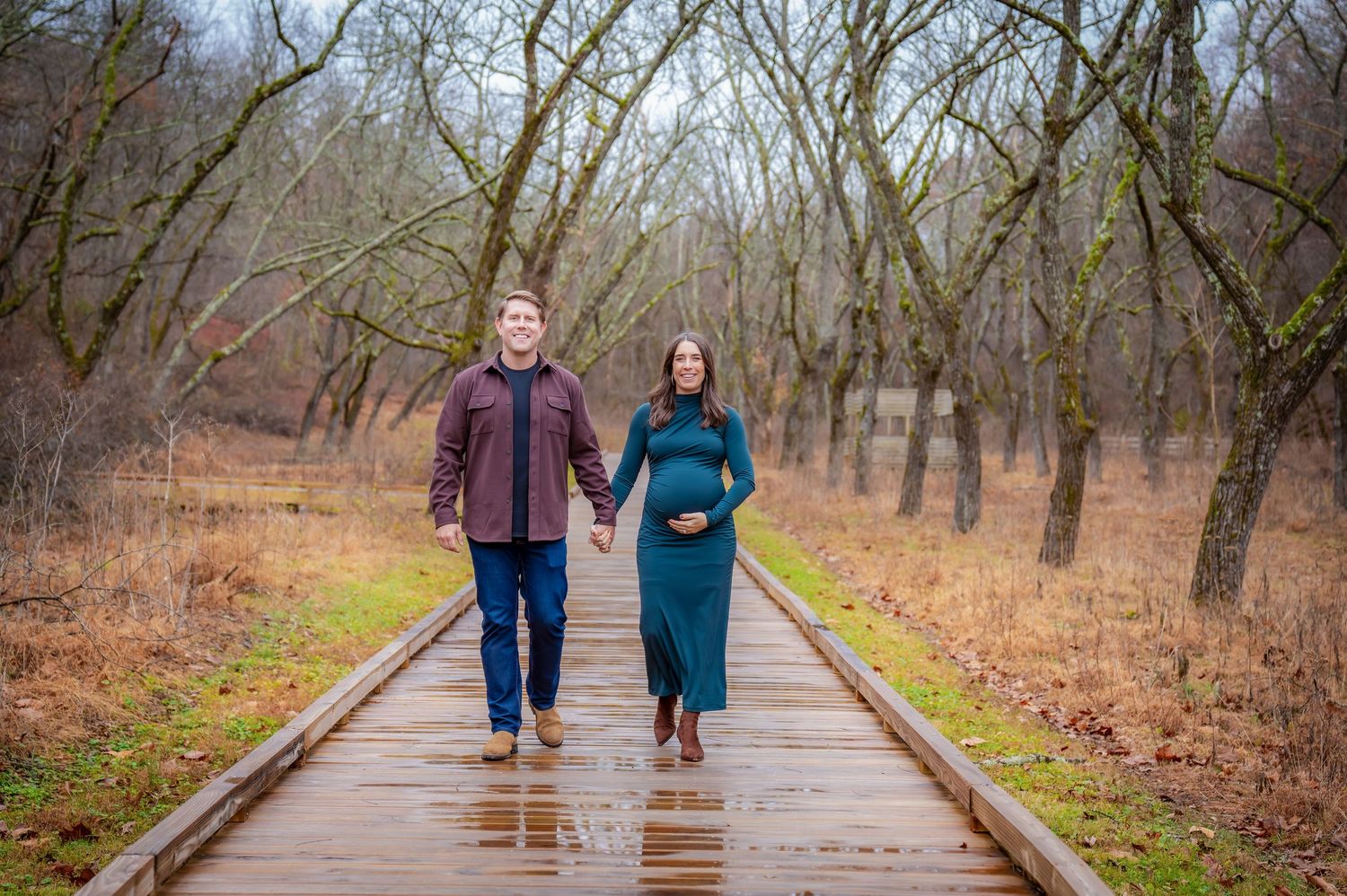 Couple strolling on a wooden boardwalk through a winter forest landscape.