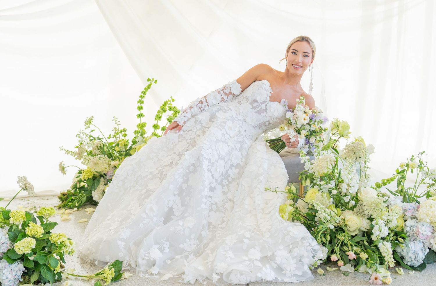 Elegant bridal portrait featuring lace wedding gown and floral backdrop.
