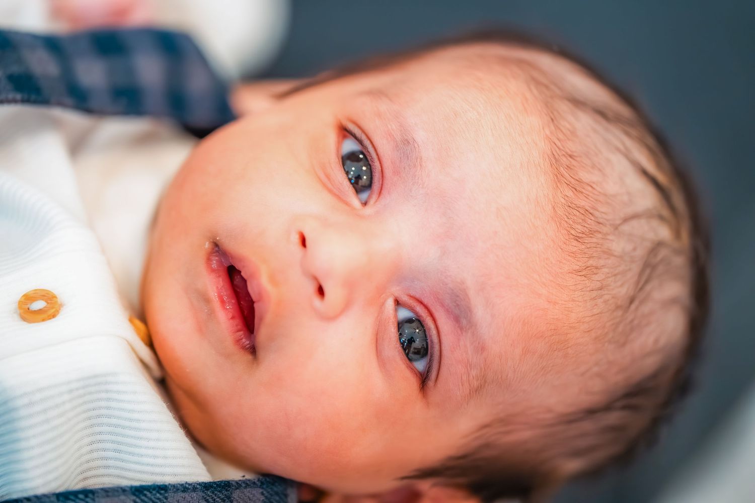 Close up portrait of infant with bright blue eyes lying on side.
