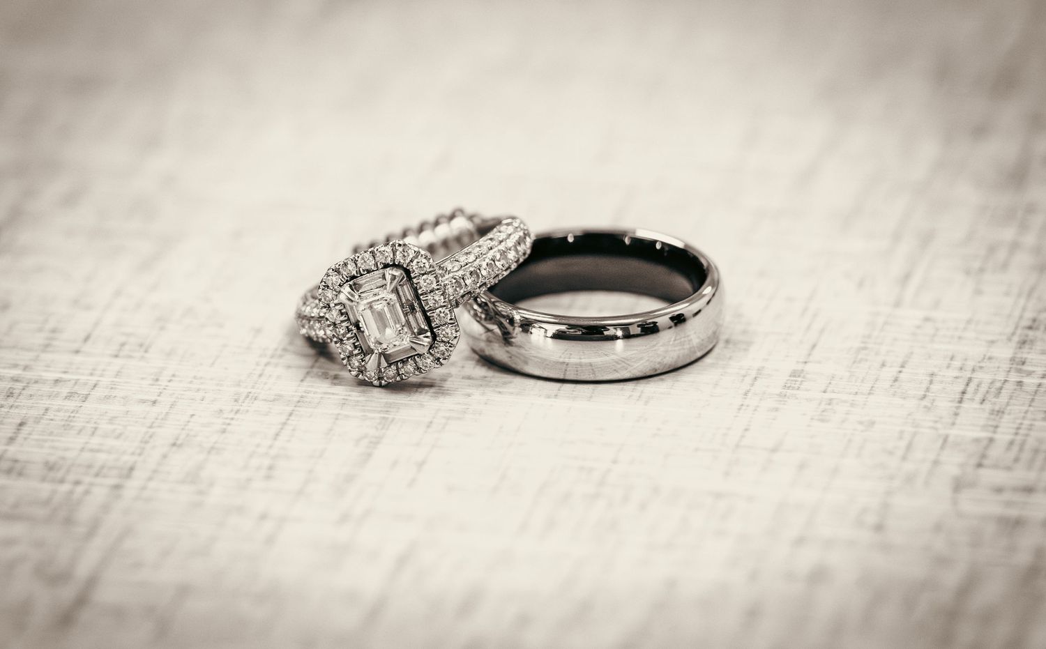 Close-up of diamond wedding rings on a textured white surface.
