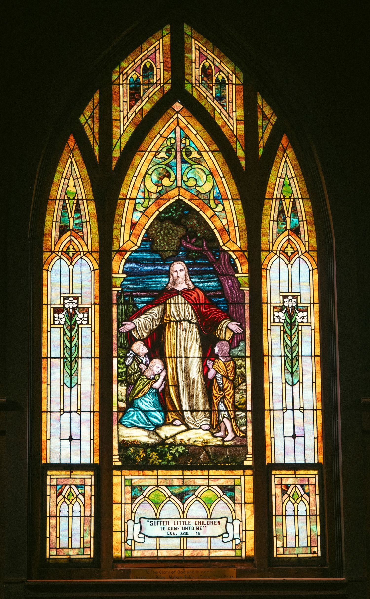 Historic stained glass church windows depicting religious scenes in rich colors and gothic arches.