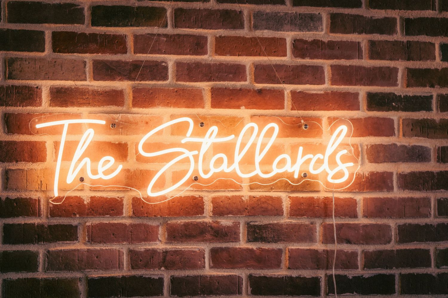Illuminated neon sign on brick wall creating romantic ambiance.