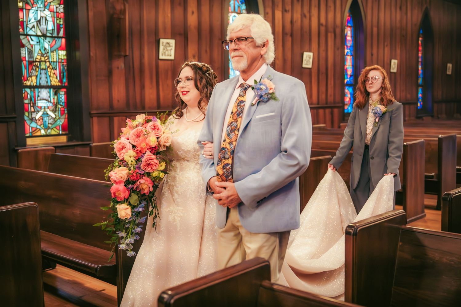 Wedding ceremony in progress inside a traditional church with stained glass windows and wooden details.