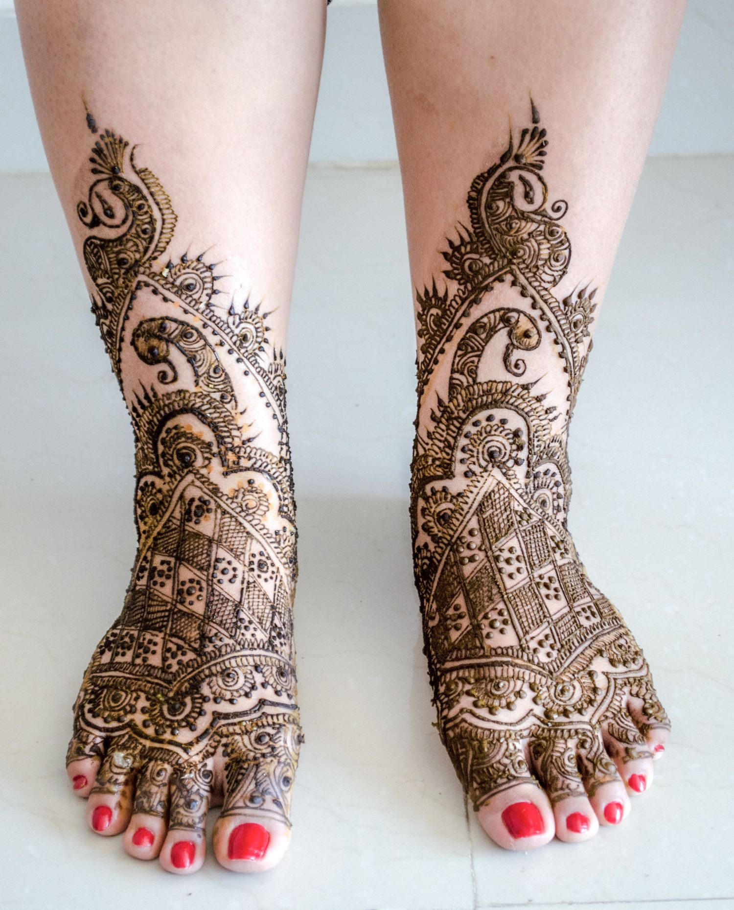 Detailed mehndi design on feet with intricate paisley and floral patterns.