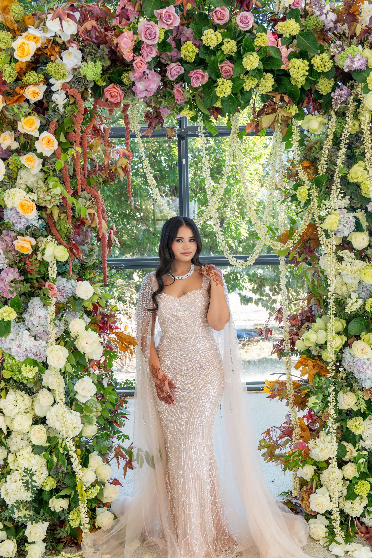 Luxurious floral arch with pink, yellow, and white roses creating a romantic wedding backdrop.