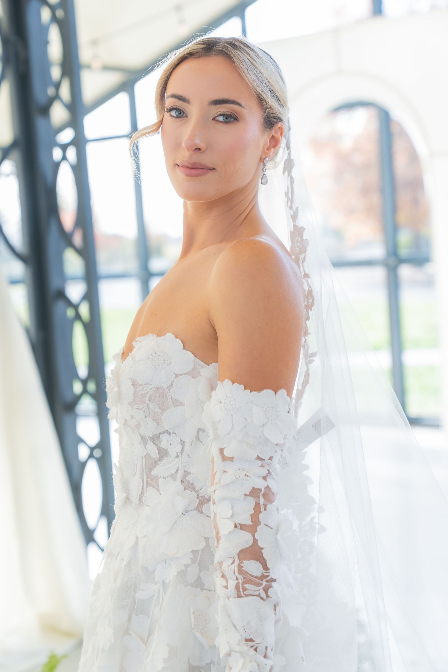 Off-shoulder lace wedding dress detail shot in natural window light.