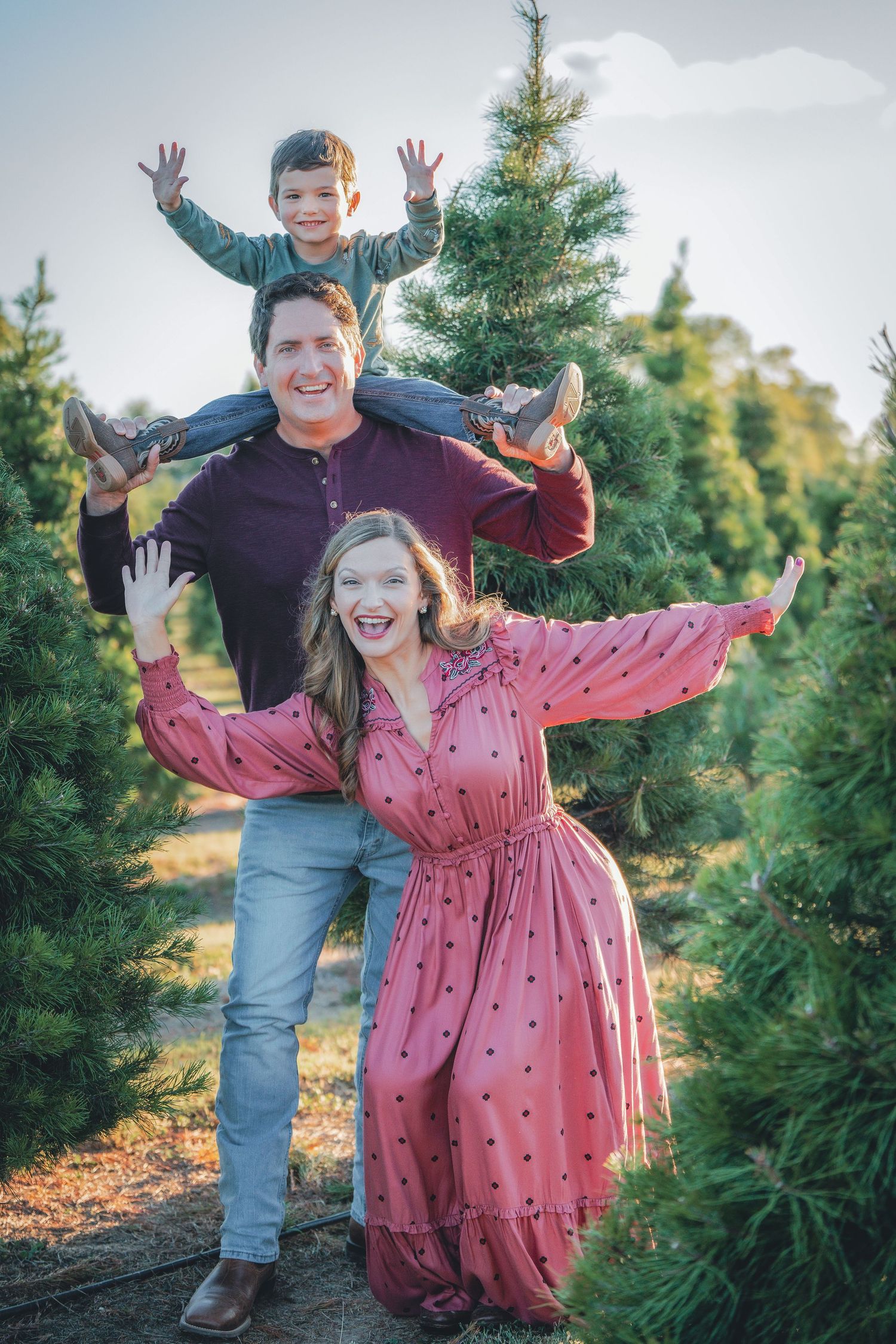 Energetic family photos among Christmas trees with joyful jumping poses.