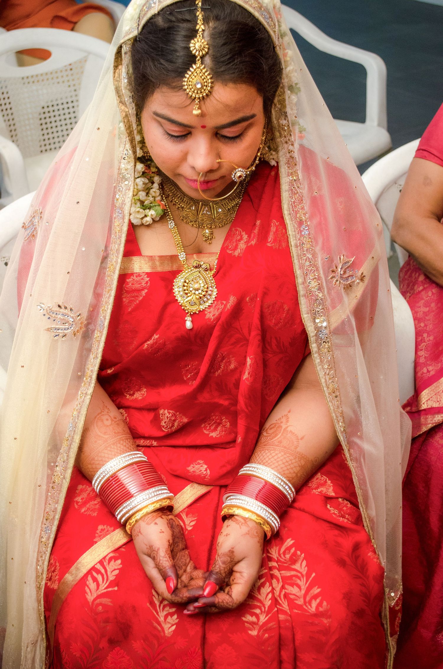 Bride in red silk saree performing traditional wedding rituals.