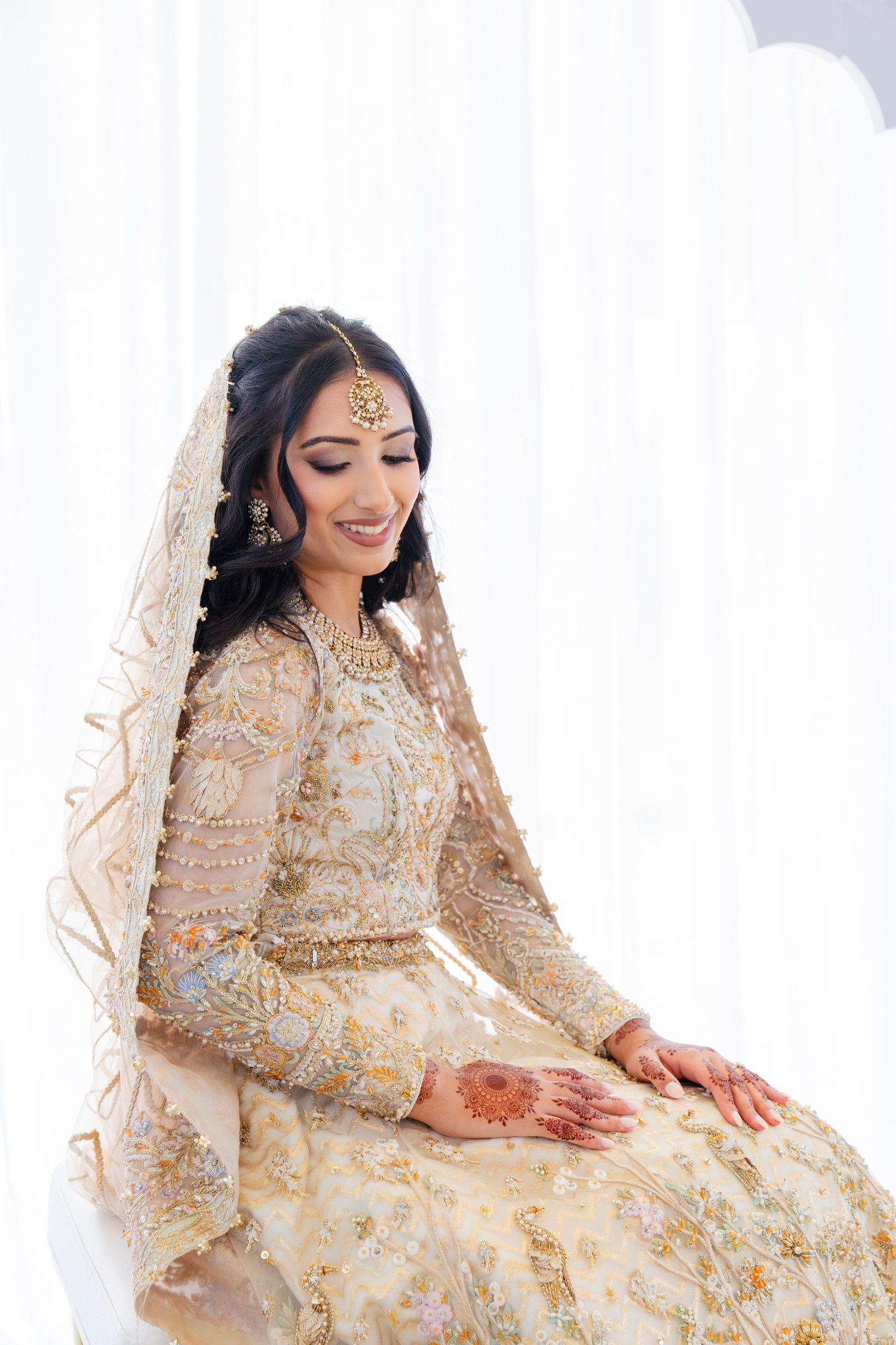 South Asian bridal fashion featuring gold embroidered dress and traditional jewelry.