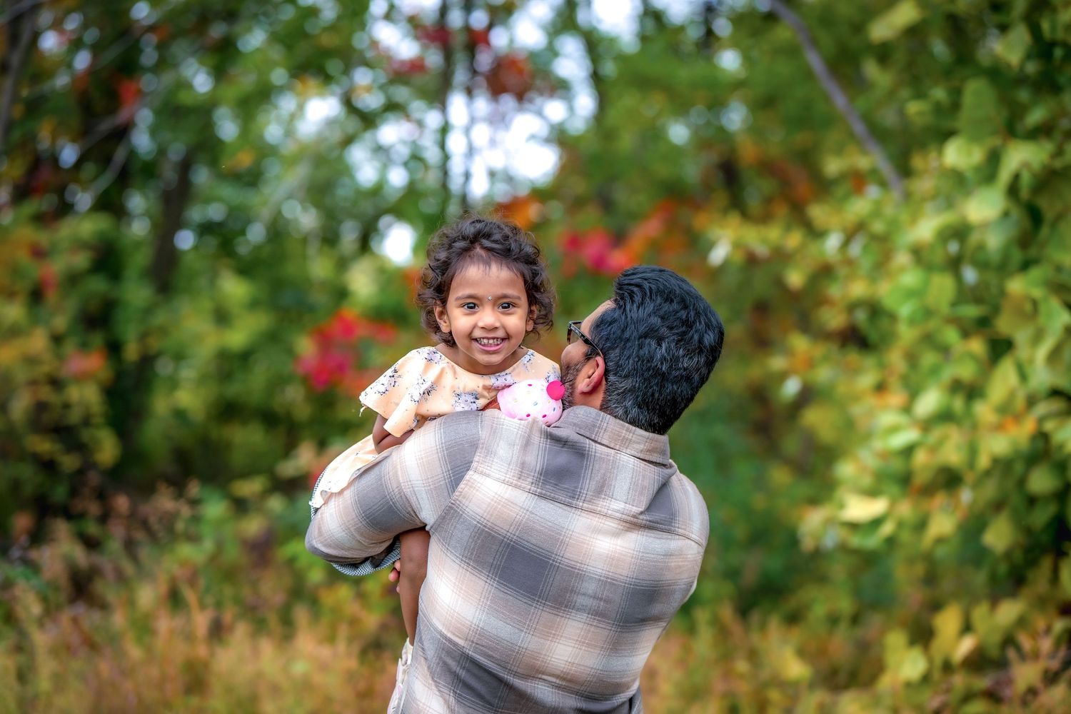 A tender moment captured between parent and child against autumn foliage.