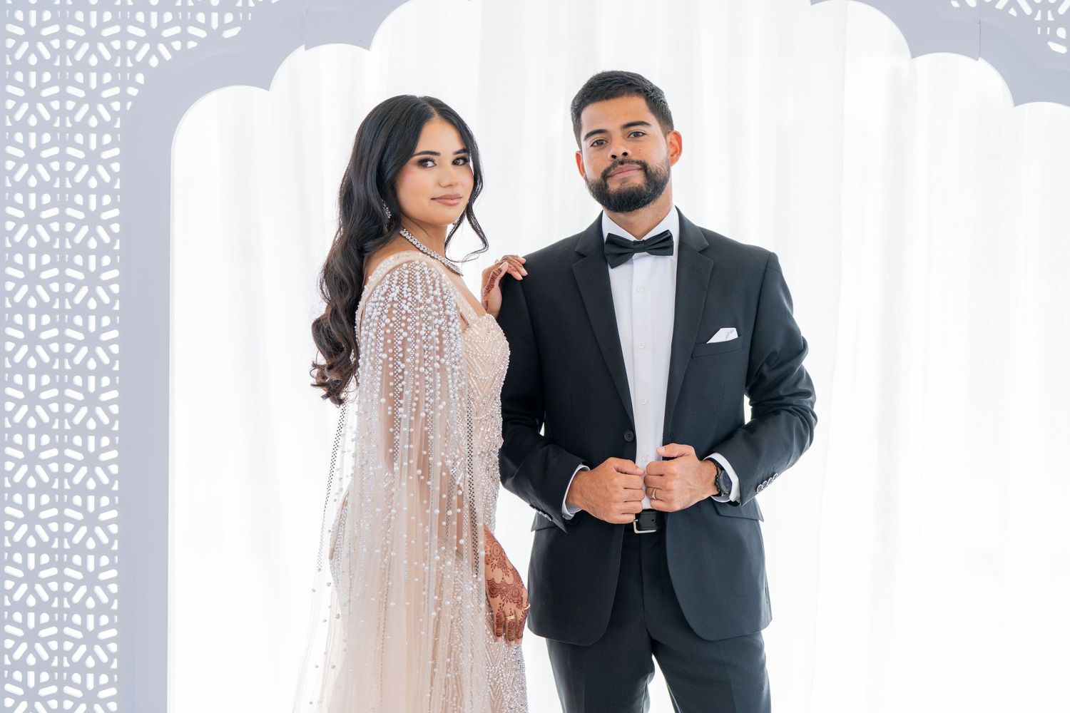 Elegant couple in formal wedding attire sharing tender moments against white backdrop.