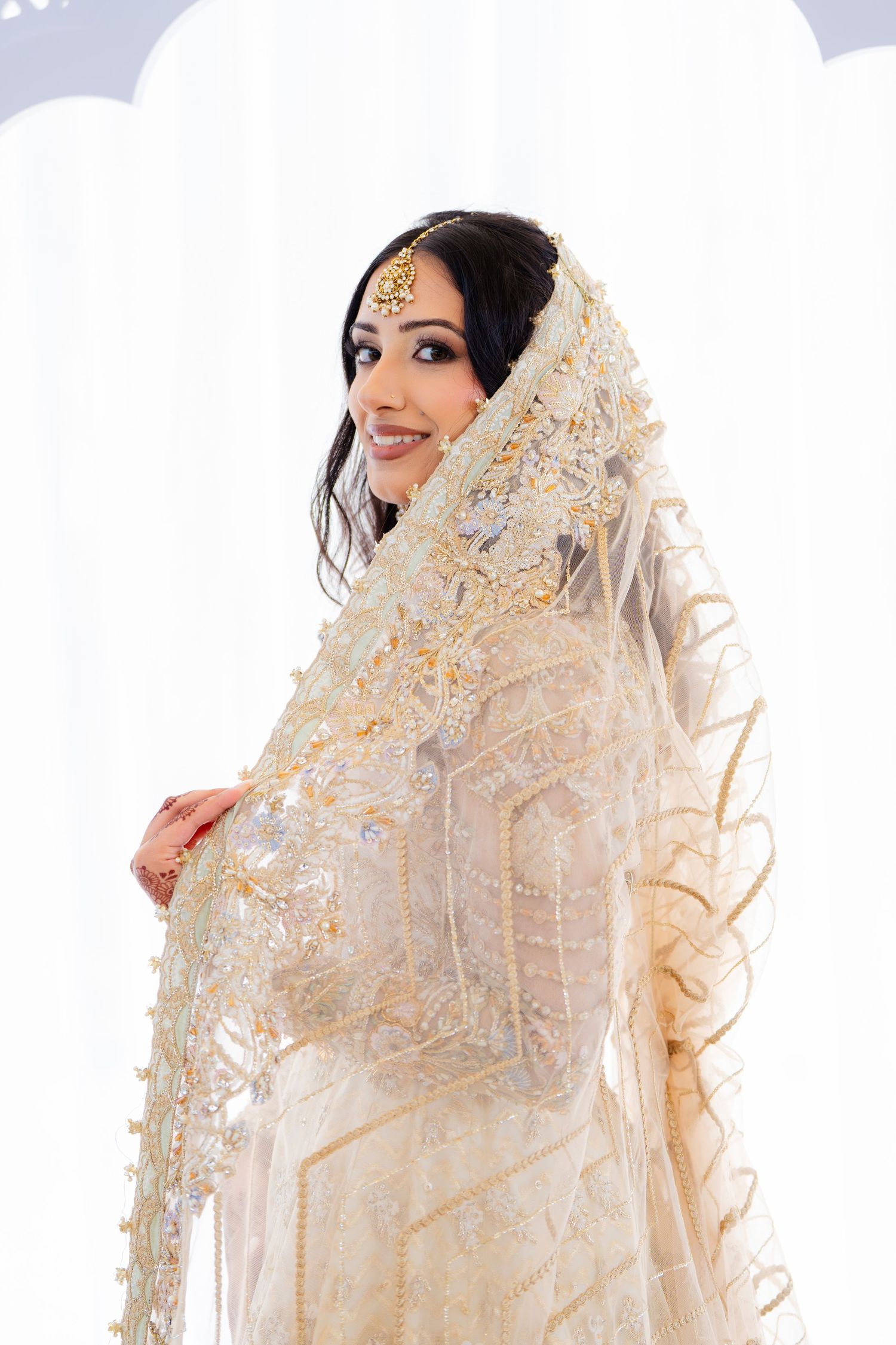 Traditional South Asian bridal attire featuring intricate beadwork and cream-colored fabric.