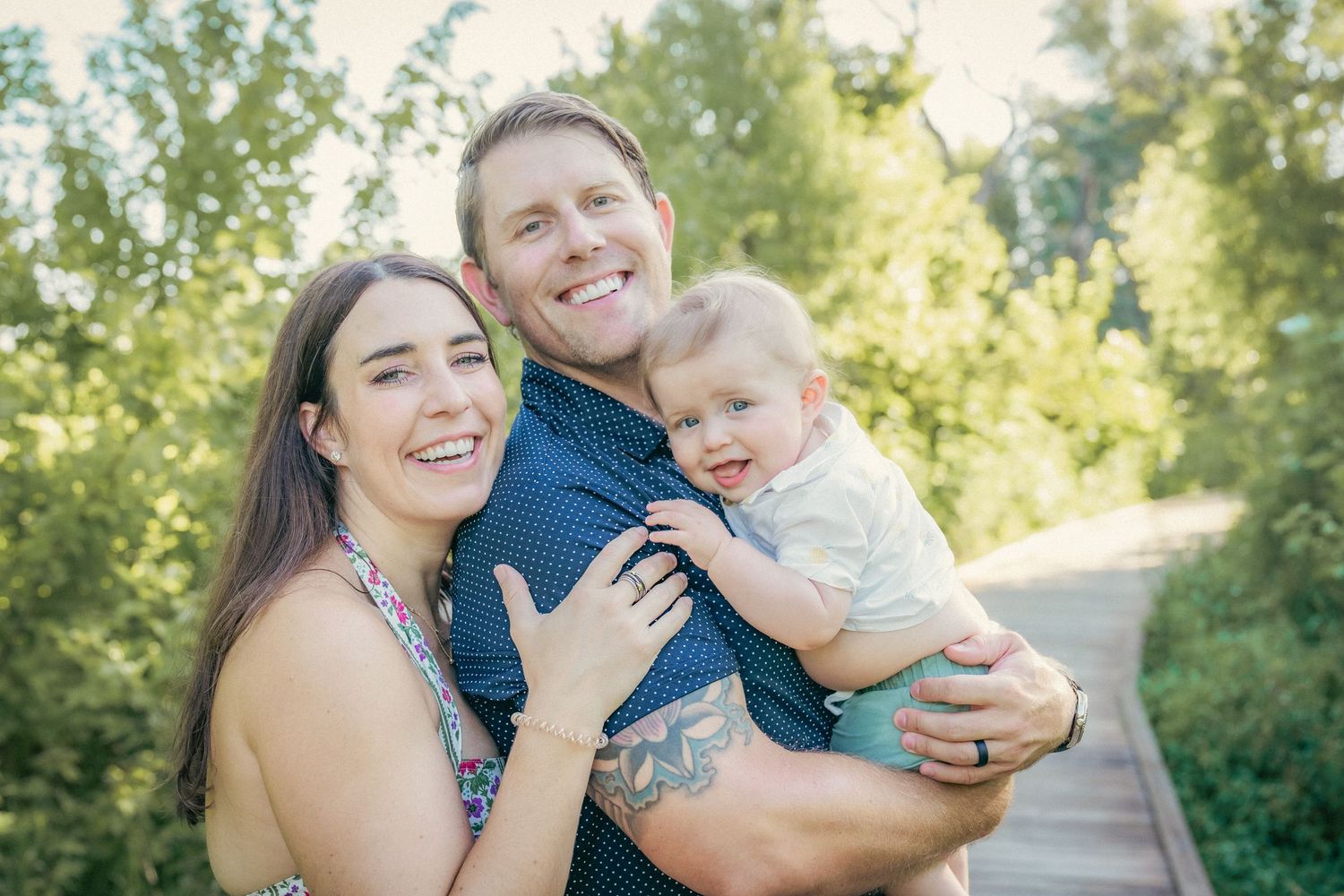Family shares joyful moments together on a wooden bridge surrounded by lush greenery.