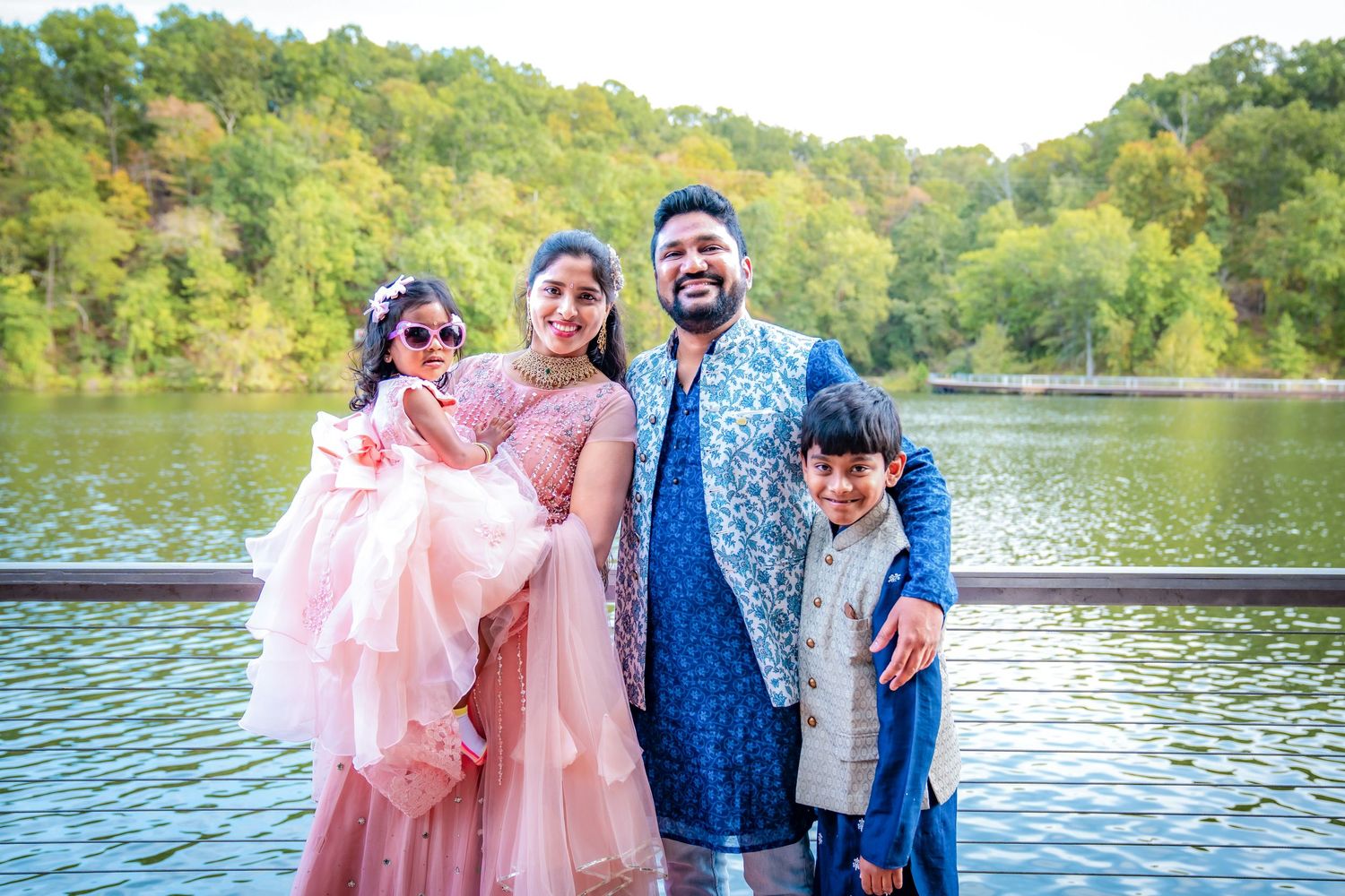 Family portrait session at sunset by a lake with coordinated pink and blue outfits.