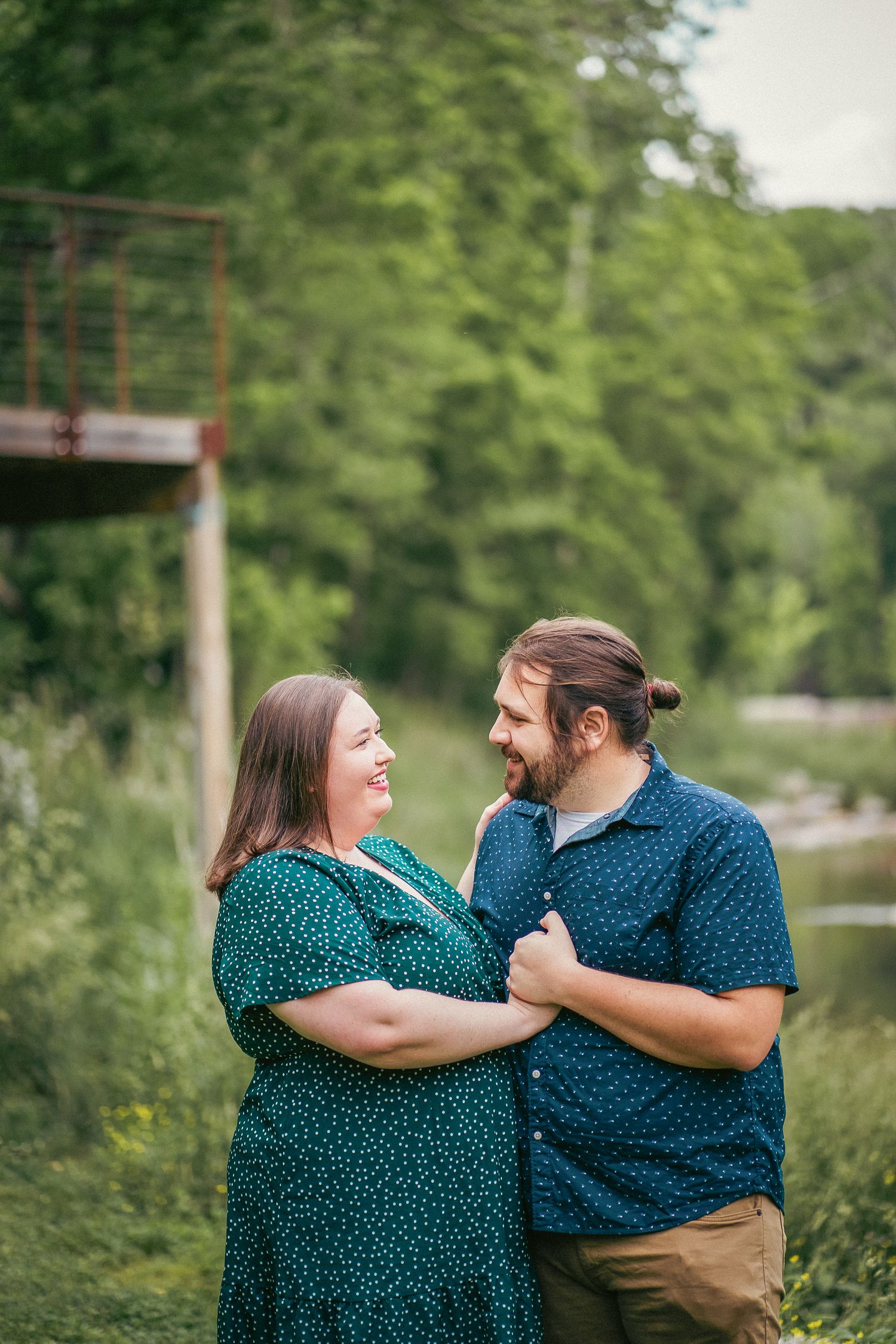 A couple wearing coordinating polka dot outfits embraces while laughing outdoors.