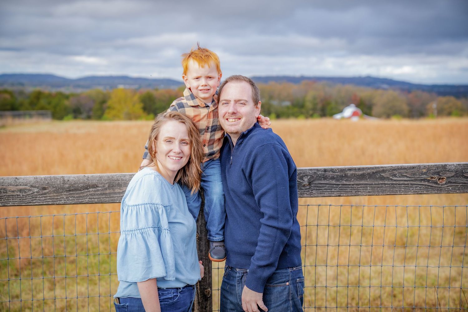 Outdoor family portrait session in field with mountains and dramatic sky.