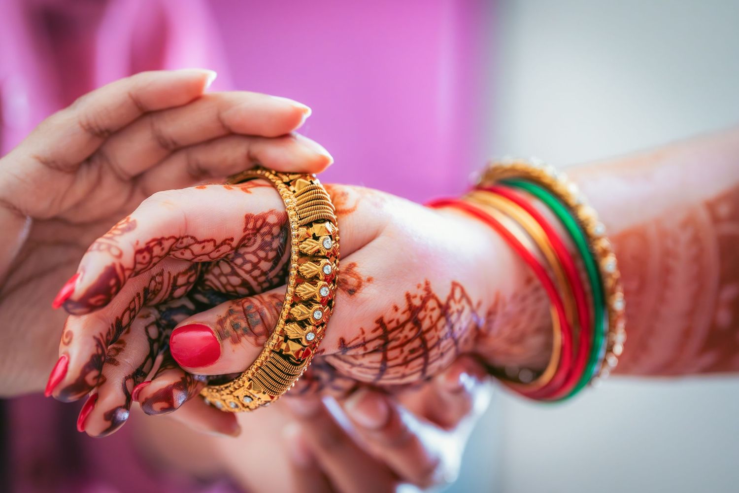 Close-up of traditional Indian wedding jewelry and bangles on decorated hands.