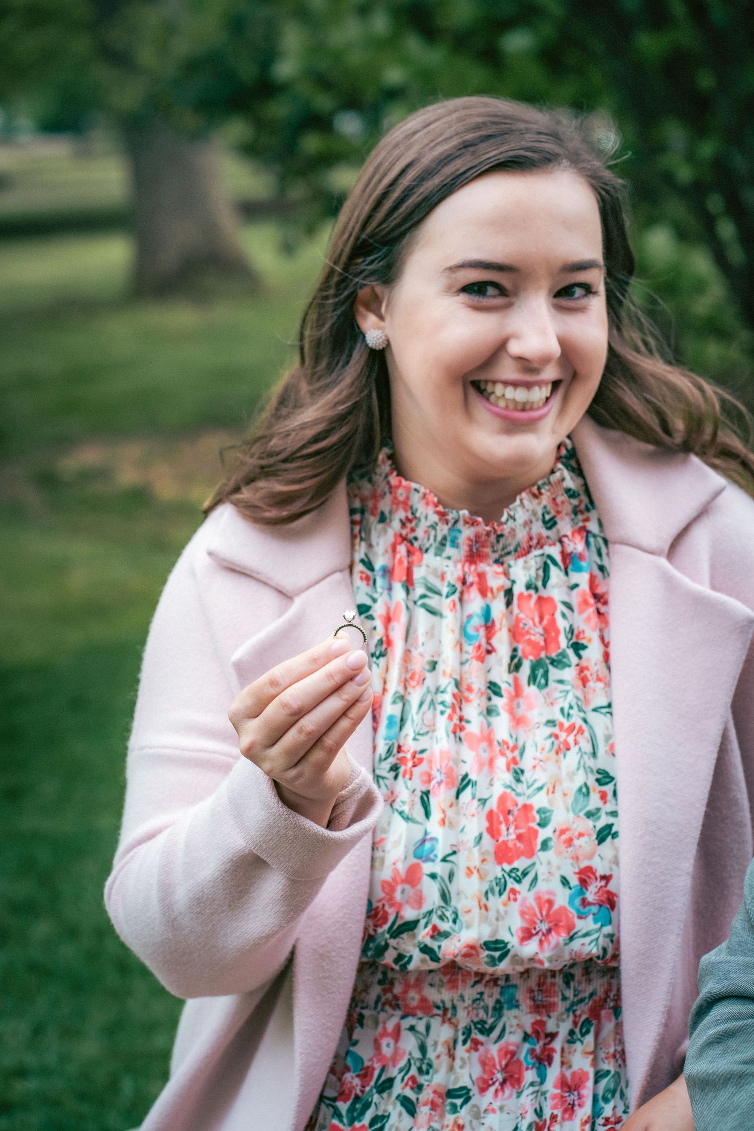 Woman in floral dress and pink cardigan shows joyful expressions.