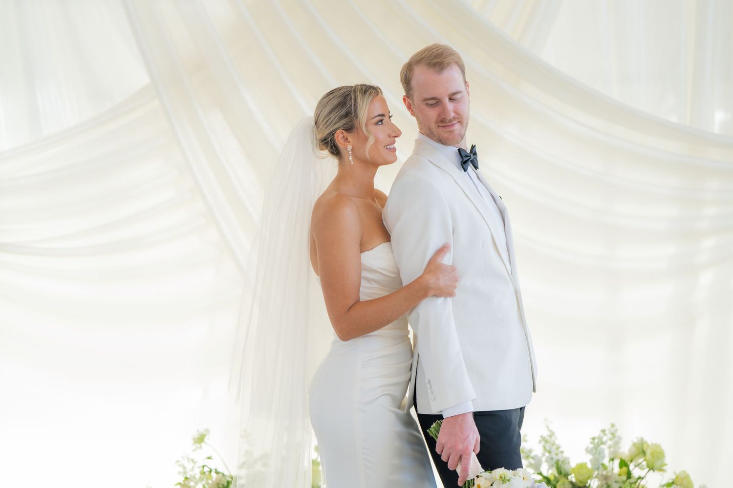 Couple shares tender moments during their wedding photoshoot in white draped tent.