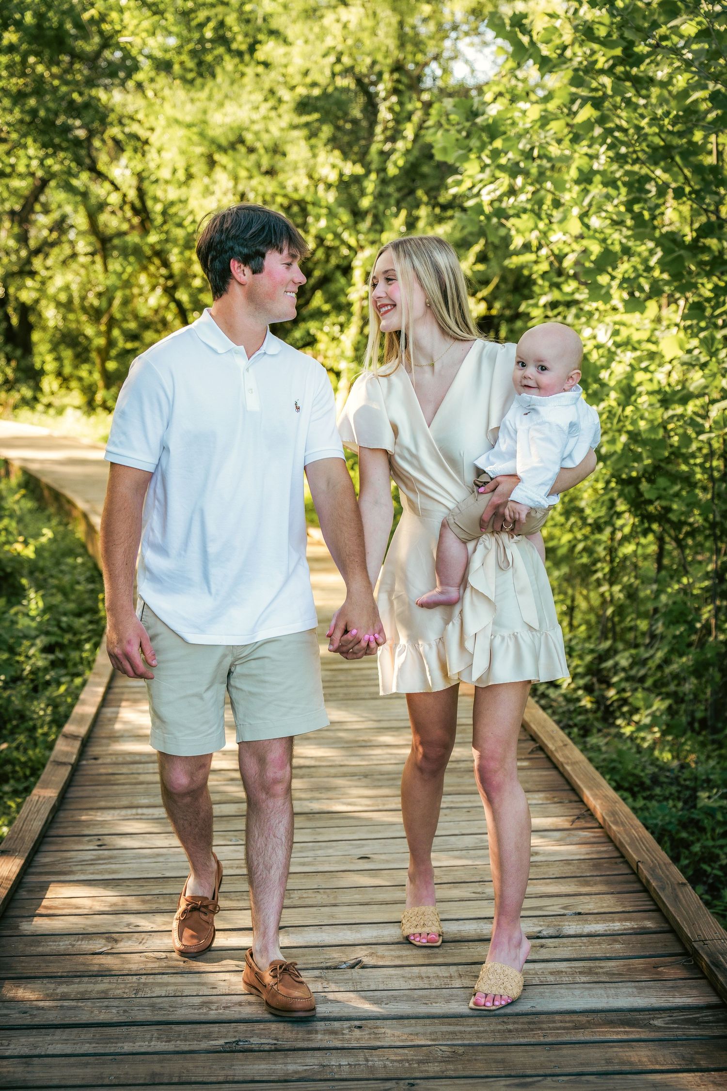 Family walking together on wooden boardwalk wearing coordinated neutral outfits.