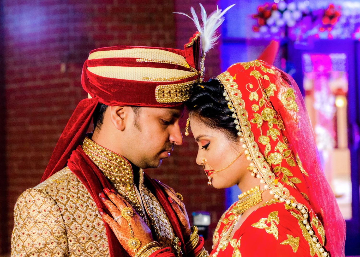 Intimate moments captured between a couple in traditional Indian wedding attire.