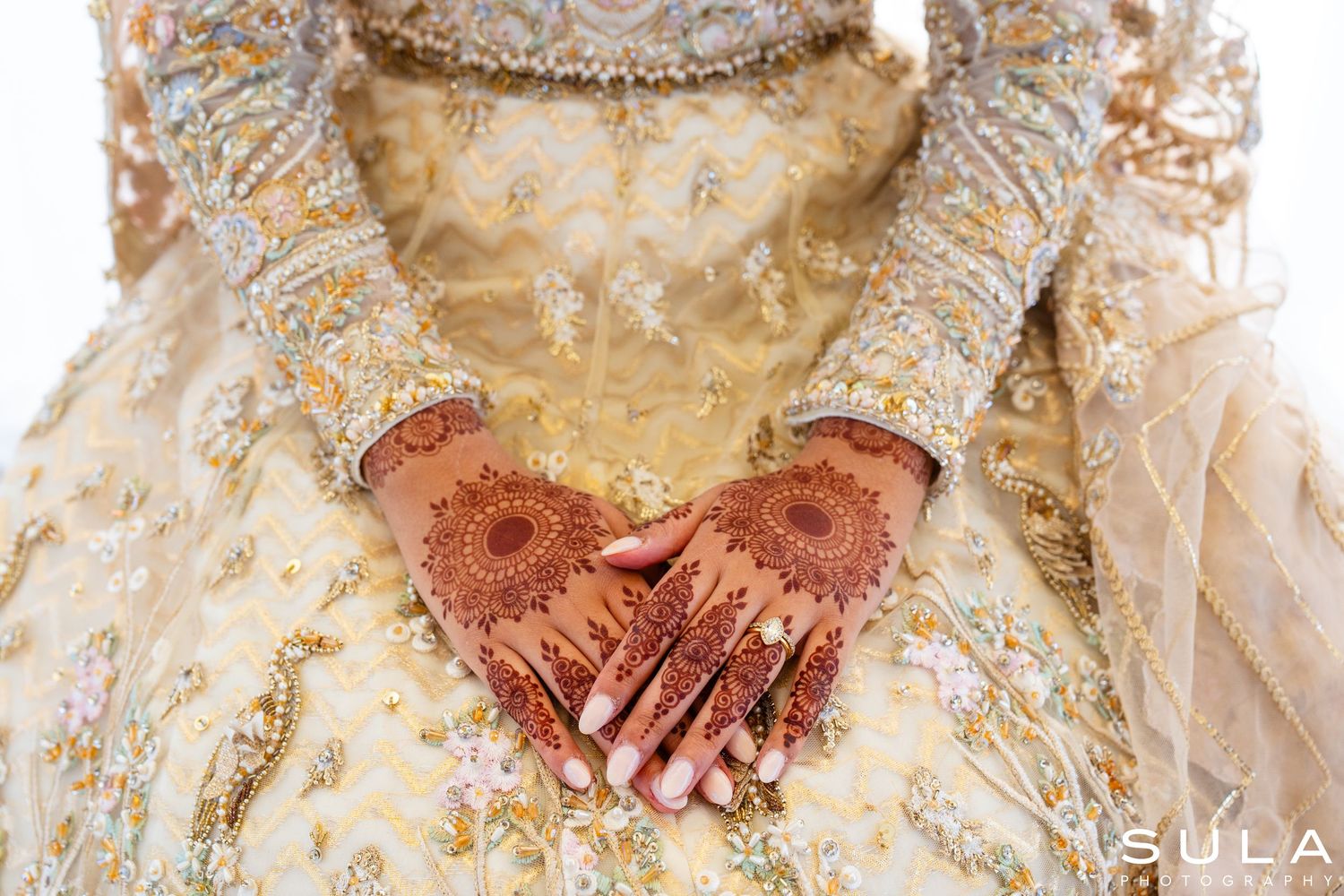 Traditional bridal details showing ornate gold jewelry and henna decorated hands.
