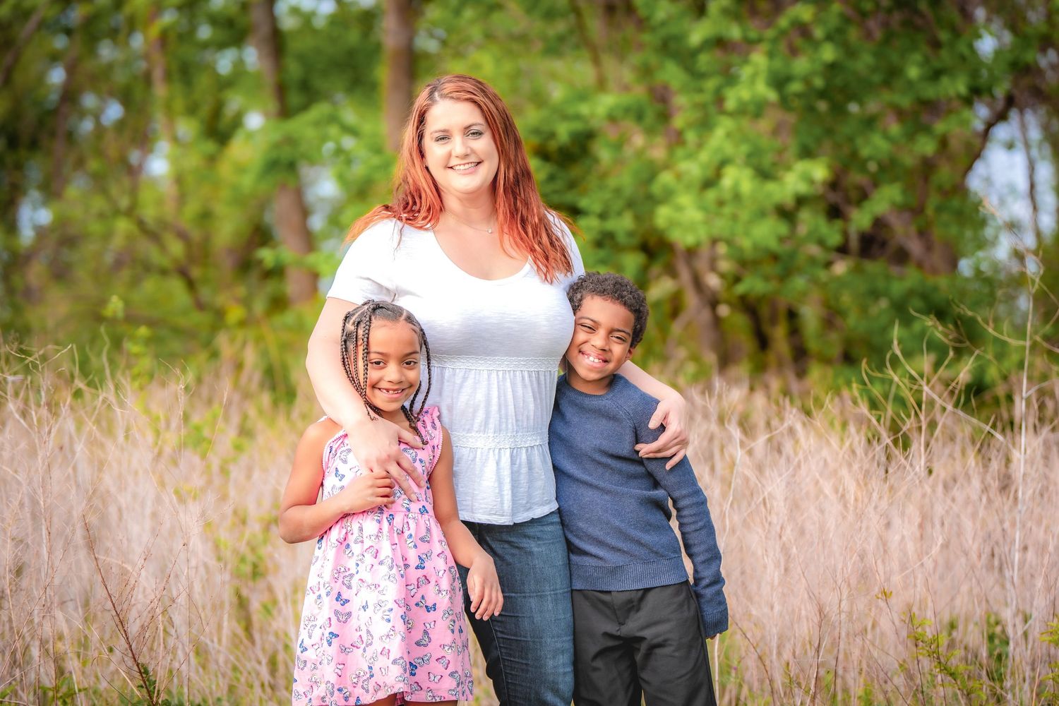 Candid family moments photographed in a field with tall grass during golden hour.
