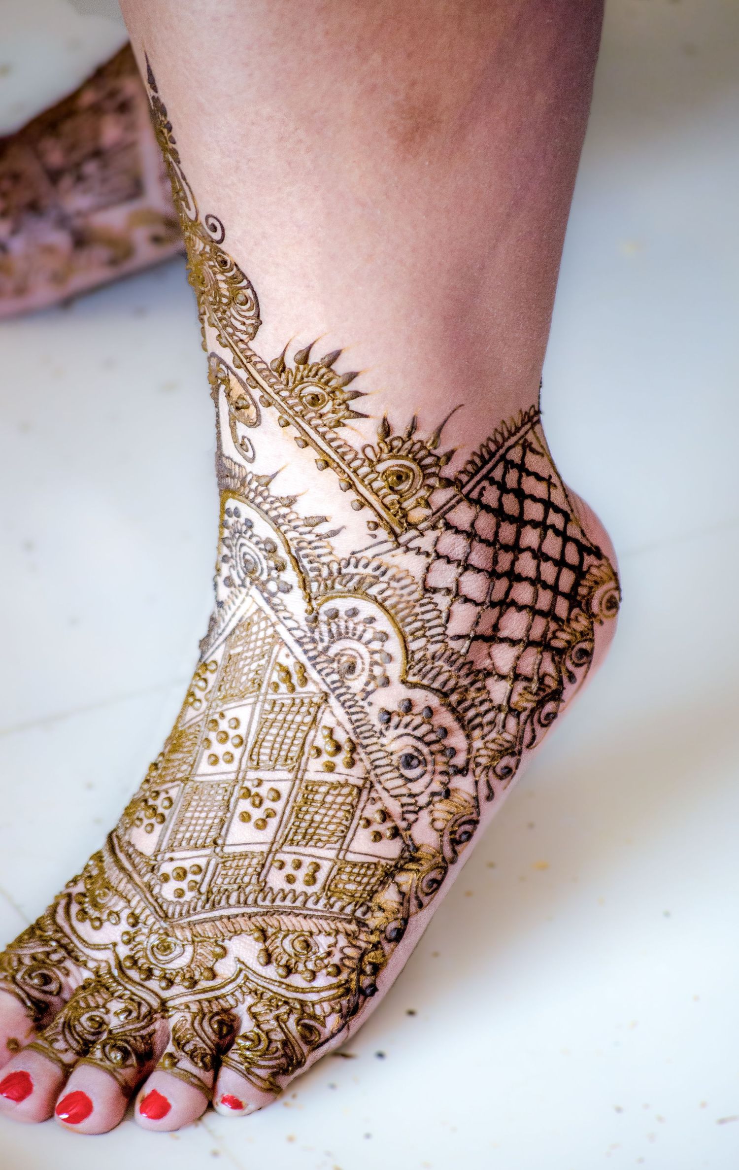 Bridal mehndi artwork on feet featuring detailed geometric and traditional patterns.