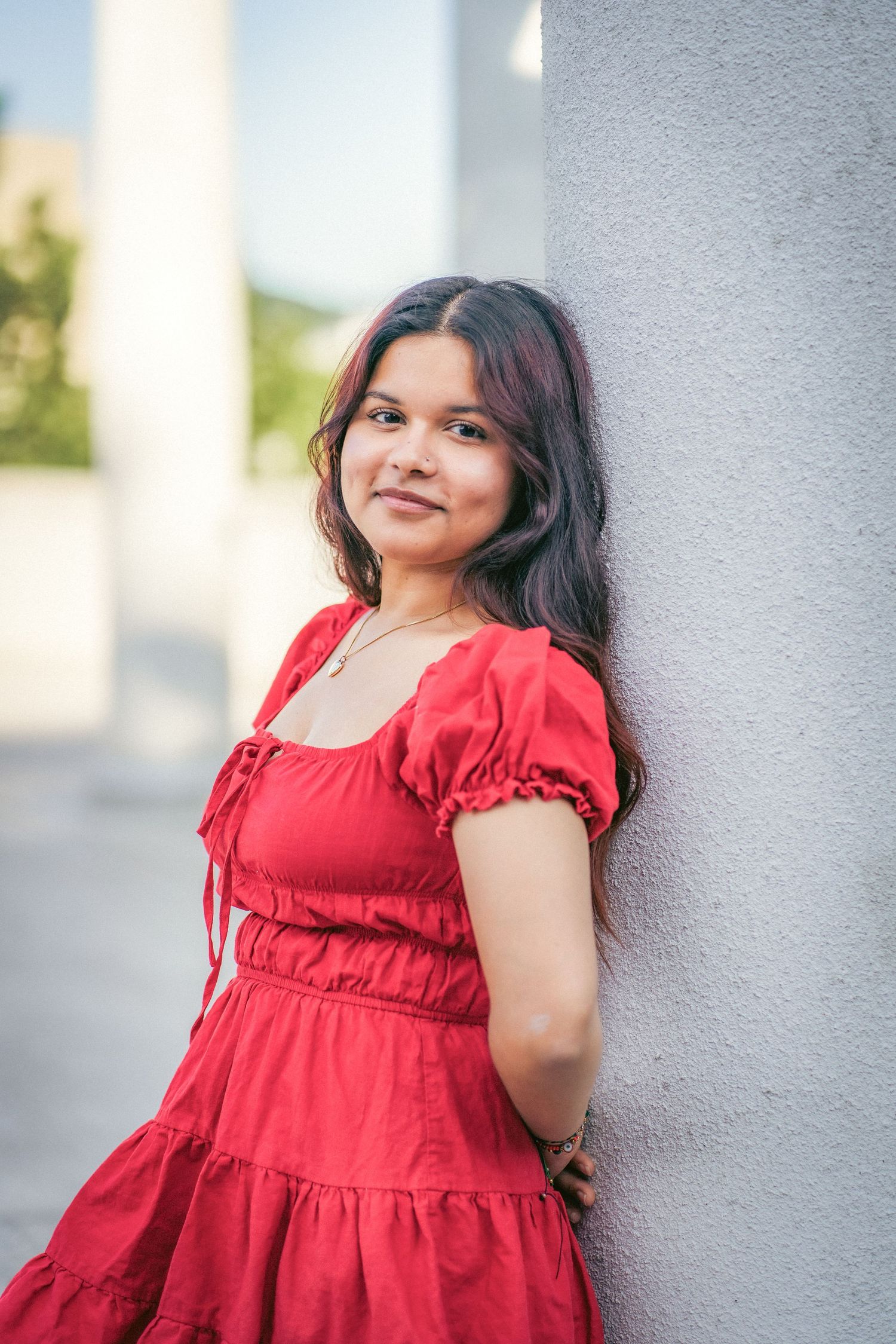 Red dress portrait against white column with natural lighting.