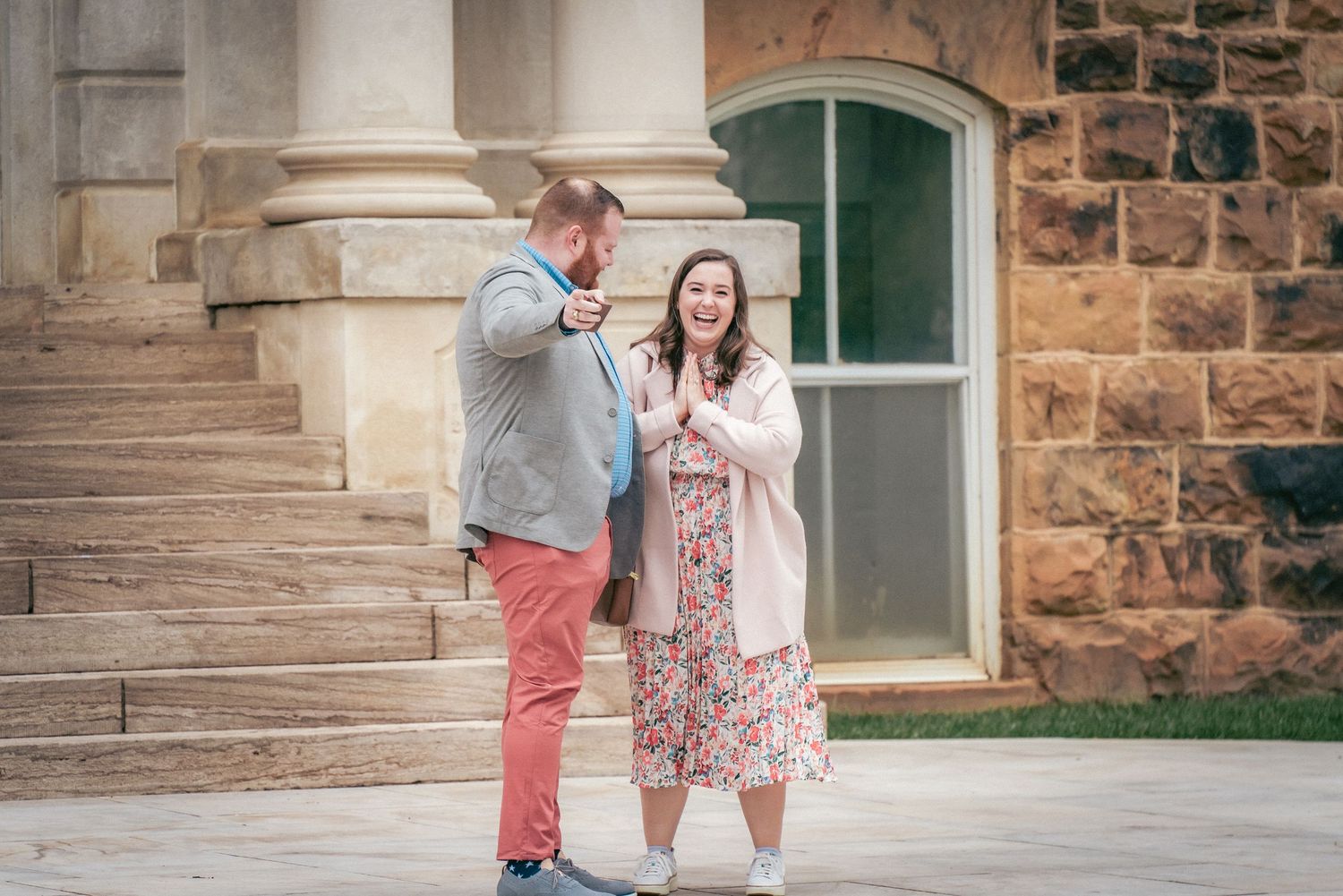 Couple poses together on stone steps of a historic building.